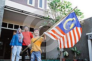 Boy rising malaysian flag with pride