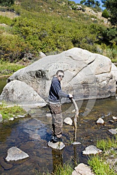 Boy in the river by a boulder