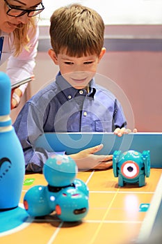 Boy at the robotics lesson. Teacher shows brand new Wonder workshop clever robot Dash. STEM