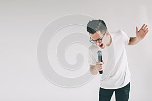 Boy Rocking Out. Image of a handsome man singing to the microphone, isolated on light. Emotional portrait of an