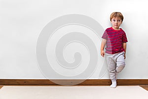 Boy with a rogue face and leaning against the wall. White background. Copy space