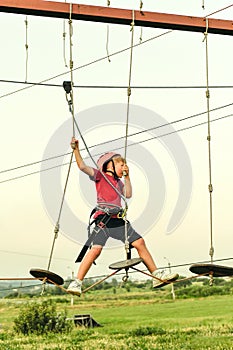 A boy on a rope overcomes obstacles in an extreme sports park photo