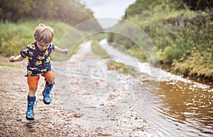 Boy with rubber boots enjoys rainy day