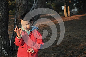 A boy in rubber boots walks through the forest and holds a magnifying glass in her hands, examines the stones, a mineral.