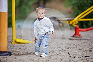 Boy rubbing his leg hit by outdoor exercise machine