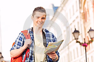 Boy with rucksack and city map on the street