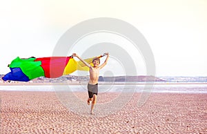 Boy run with a color parachute fabric fly on wind