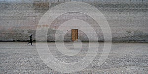 Boy running in front of wooden door on brick wall