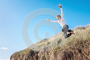 Boy running and jumping over sand dunes on beach vacation background