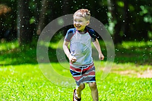 Boy running outdoors in sprinkler