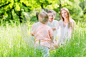 Boy running and playing on meadow with the family