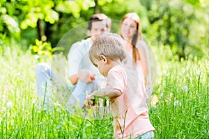 Boy running and playing on meadow with the family