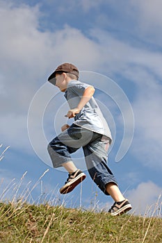 A boy running up a grass hill