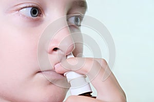 A boy with a runny nose holds a medicine in her hand, nasal spray irrigations to stop allergic rhinitis and sinusitis