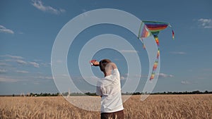 A boy runs across the field at sunset with a kite flying over his head. A chidhood dream. Kids Games