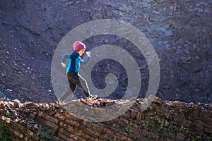 A boy runs along a mountain path