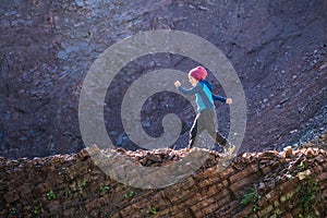 A boy runs along a mountain path