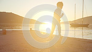A boy runs along the pier by the sea at sunset