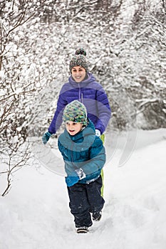 The boy runs away from his mother on a snowy path