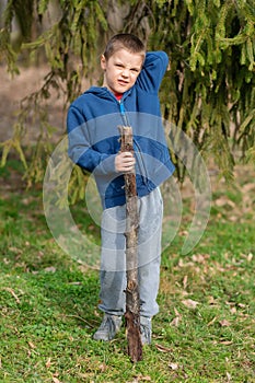 A boy runs in nature with a wooden stick. Little boy play with stick in forest