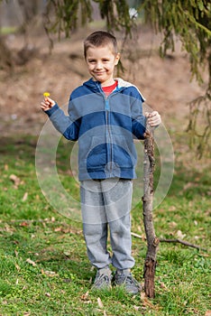A boy runs in nature with a wooden stick. Little boy play with stick in forest