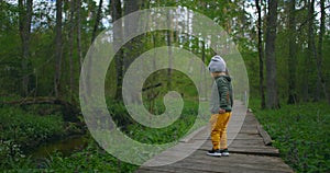 A boy runs in a Park on a wooden path in slow motion. Adventure of a boy in the forest. A 2-3 year old boy runs over a