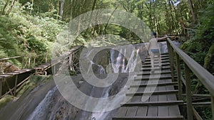 The boy runs up the wooden stairs against the backdrop of a waterfall. CREATIVE. Wooden stairs and ceilings in front of