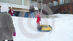 A boy runs uphill to ride a tubing. Sliding