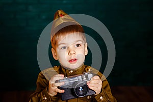 Boy in russian military uniform with camera. Child war correspondent