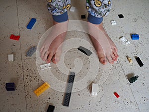 The boy`s bare feet next to the scattered blocks