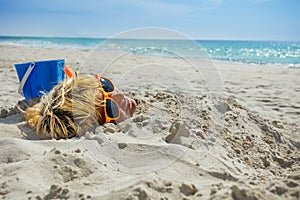 Boy& x27;s face dug into sand on the beach over sea