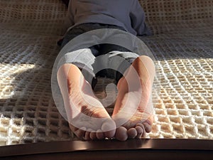 Boy`s feet on bed close-up. Boy lying on bed and reading a book