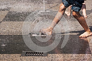 Boy's feet in blue jeans playing in the fountain