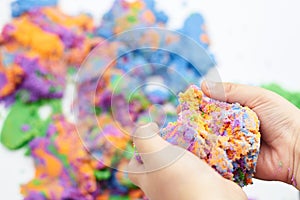 The boy`s hands are squeezing bright kinetic sand