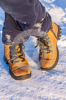 The boy`s legs in boots standing on snow