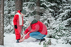 The boy`s shoes are unbuttoned, the man from zips up in the winter forest during a walk