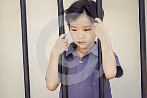 Boy sad behind the iron bar