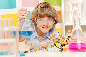 Boy in safety goggles holding flask at the lab