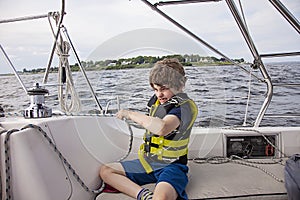 Boy sailing pulling ropes to adjust sails on sailboat