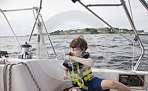 Boy sailing pulling ropes to adjust sails on sailboat photo