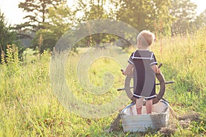 Boy in sailor suit in boat on grass