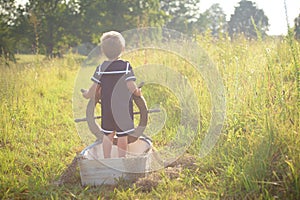 Boy in sailor suit in boat on grass