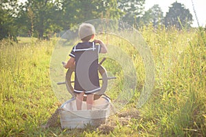 Boy in sailor suit playing in boat on grass