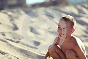 Boy in sand on beach smiling