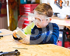 Boy sanding wooden block in workshop photo