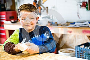 Boy sanding wooden block in workshop photo