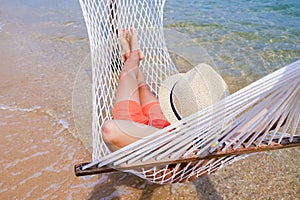 Boy with sandy feet lying in a hammock at the beach. Cozy hammock on the tropical beach by the sea. Copy space banner