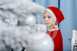 Boy in santa costume. Kid concept for merry Christmas and happy new year celebration. Small boy enjoys playing piano for