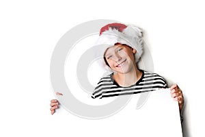 Boy in Santa`s hat surprised and holding white blank billboard for greetings. Isolated on white