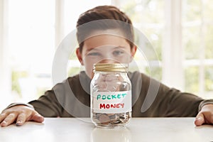 Boy Saving Pocket Money In Glass Jar At Home